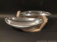 Front angle showing both aluminum banana boat shaped bowls on the bleached wood stand.