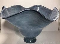 Front view of ruffled edge glass bowl on pedestal base, showing shape and color