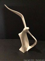 Front view of white ceramic flying seagull sculpture with elongated wings and abstract closed loop body design.