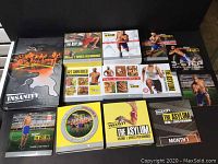 Photo showing a collection of fitness DVDs from the Insanity program and related workout series, including The Asylum volumes, Get Shredded, and 3-Step To Shred, along with printed materials.