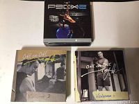 Photo showing P90X2 DVD set on top and One on One Series Volumes 1 and 2 DVDs below it with signed covers
