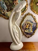 Side view of tall white glossy porcelain figurine depicting a couple with newborn baby in a modern abstract style.