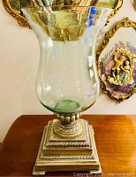 Full view of large clear glass footed vase on decorative base showing overall size and shape.