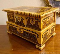 Closed view of vintage wooden jewelry box showing inlaid wood designs and rounded feet