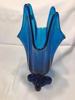 Front view of vintage Viking cobalt blue art glass vase with four pointed lotus swirl design and rounded base.