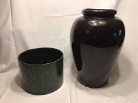 Black ceramic vase and Haeger pottery flower pot shown side by side against a white fabric backdrop.