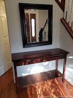 Framed wall mirror above the hall table, showing overall size and appearance in a stairway area.