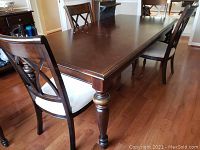 Full view of dark wood rectangular dining table with matching chairs, showing table top and legs
