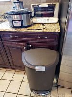 Photo showing two stainless steel slow cookers on a kitchen counter beside a white toaster oven and a dark matte finish trash can on the floor.