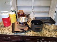 Overview of all items on granite countertop including cookware, thermos jugs, basket, and vase.