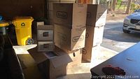 Seven stacked boxes labeled Sterilite 2310-4 Pc 27 Qt Drawer, with some boxes open showing translucent white storage drawer units.