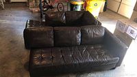 Front angle view of larger sectional sofa piece showing brown leather-like upholstery with tufted seat cushions, three removable back cushions, and modern design.