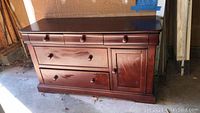 Front view of the dark brown wooden buffet showing drawers and cabinet door with knobs.