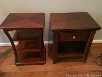 Two wood side tables standing side by side on a wooden floor, one with drawer, one with two shelves, medium brown color with minor surface wear.