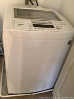Front and left side view of white LG top load washer showing overall condition and design