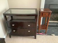 Front view of dark wood two drawer chest with a glass top and matching small vintage wooden stand with one drawer.