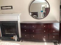 Wide shot of the dresser and matching round mirror mounted above a fireplace.