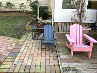 Wide shot showing metal firepit on brick patio with two children's Adirondack chairs beside a wooden deck.