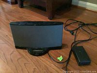 Full view of Bose SoundDock Series II speaker with attached power adapter and cord on hardwood floor