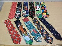 Top-down view of all 11 Christmas neckties arranged flat exposing their designs and colors.
