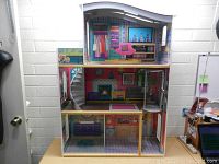 Front view of the large three-floor doll house showing multiple rooms and detailed printed interior.