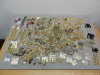 Large assortment of costume jewelry laid out on a table including multiple types of necklaces, earrings, bracelets, and brooches in various colors and styles.