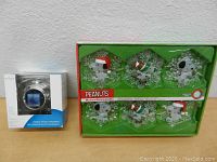 Photo showing the Peanuts musical string lights with Snoopy character ornaments in original packaging alongside the boxed digital photo ornament.