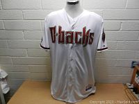 Front view of the white Arizona Diamondbacks baseball jersey showing the 'D-backs' embroidery and button-up design.