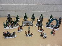 Front view of the lot showing assorted Christmas village accessories including trees, figurines, gazebo, archway, and horse-drawn carriage.