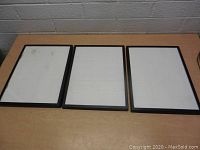 Top view showing three black framed jewelry displays with glass lids and white interiors with horizontal slots.