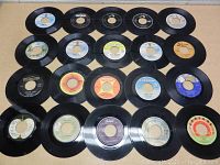 Overview photo showing all 20 45 RPM vinyl records arranged in four rows with visible labels and record company logos.