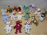 Overhead photo showing full layout of 16 assorted holiday-themed Beanie Babies on table.