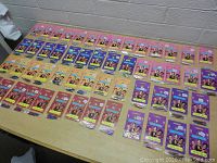 Overview of all 54 packs of Roley Poleys Fun Hair Decorations arranged on a table in rows, showing assorted colors and styles of packaging.