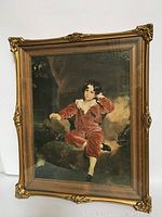 Full view of the vintage portrait print in an ornate gold frame depicting a boy in red velvet suit, seated against a dark background.