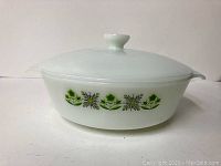 Side view of white glass casserole dish showing size and green floral pattern.