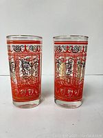 Pair of vintage drinking glasses with orange and gold ornate patterns, showing overall look and size.