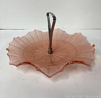 Side angle showing the scalloped edge and metal handle attached to the frosted pink glass dish.