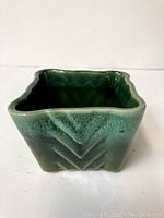 Front angle view showing textured chevron pattern on exterior of green ceramic pot.