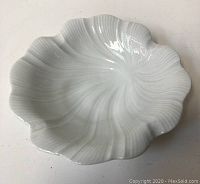 Close-up photo of white ceramic dish showing scalloped edges and glossy finish.
