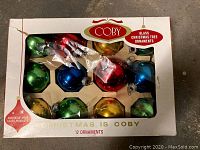 Photo of original Coby box containing 12 colorful glass Christmas ball ornaments, showing assortment of colors and packaging condition.