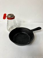 Cast iron skillet and vintage nut grinder together on white background