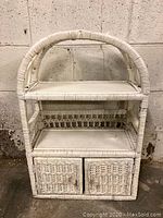 Front view of white wicker shelf with two shelves and two bottom cabinet doors.