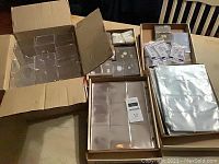 Box showing the various card collecting supplies including album sleeves, display cubes, and plastic holders all arranged and boxed for pickup.