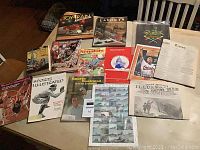 Photo showing collection of vintage magazines, books, programs, stamp sheet, and historical papers arranged on a table.