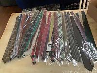 Photo showing 36 assorted men's dress ties individually packaged in clear plastic sleeves, displayed on a table with various colors and patterns visible.