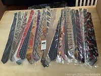36 brand new men's dress ties individually packaged, assorted colors and styles, laid out on a table
