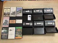 Photo showing 15 VHS train videos with cases, arranged on table.