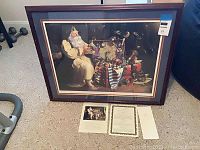 Full view of the framed art print depicting Santa Claus with toys and certificate of authenticity laid out on floor, showing overall condition and content