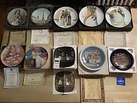 Full spread of 10 assorted collector plates with their original foam-lined boxes and accompanying Certificates of Authenticity laid out on green carpet.