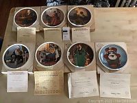 Seven round Edwin Knowles Norman Rockwell Mothers Day plates from 1979 through 1985 arranged on table with Certificates of Authenticity in front.